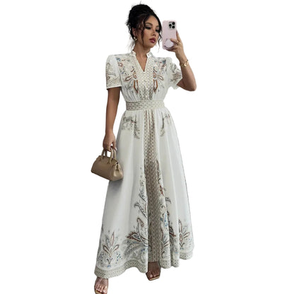 Woman in a white embroidered dress taking a mirror selfie in a room with gray flooring and white curtains.